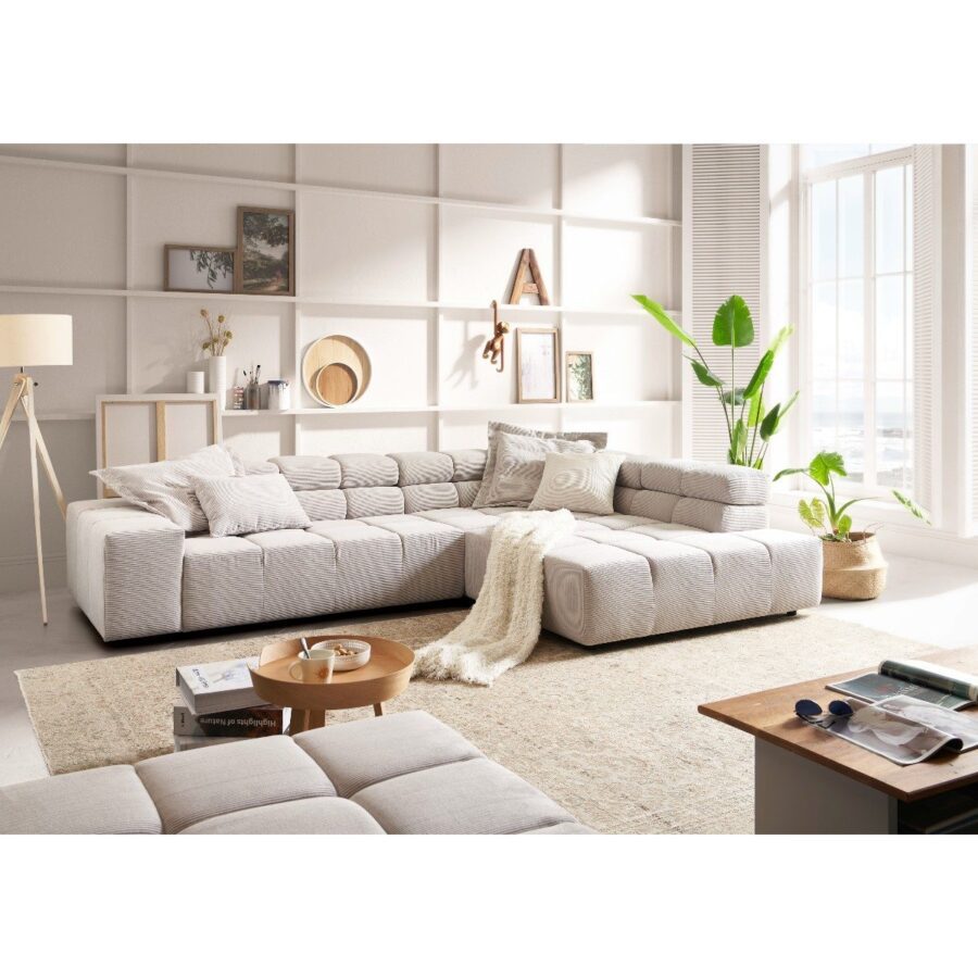 Candy Careno Ecksofa mit verstellbaren Kopfstützen und Ottomane rechts in Feincord Silber als Wohnbeispiel.